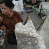 A woman blows on a batik tool
