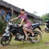 A young Dyak woman poses on a motor bike