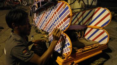 A Jokowi supporter paints his becak in the new president's trademark check